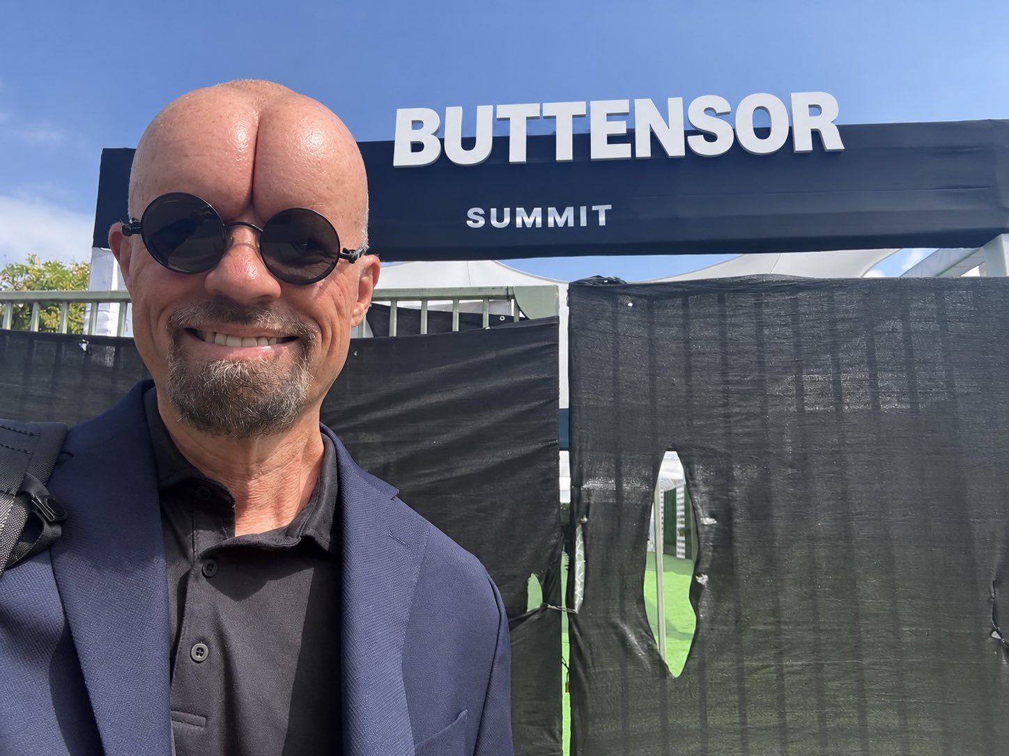 A smiling person at a BUTTensor summit display with a digitally altered rounded head.